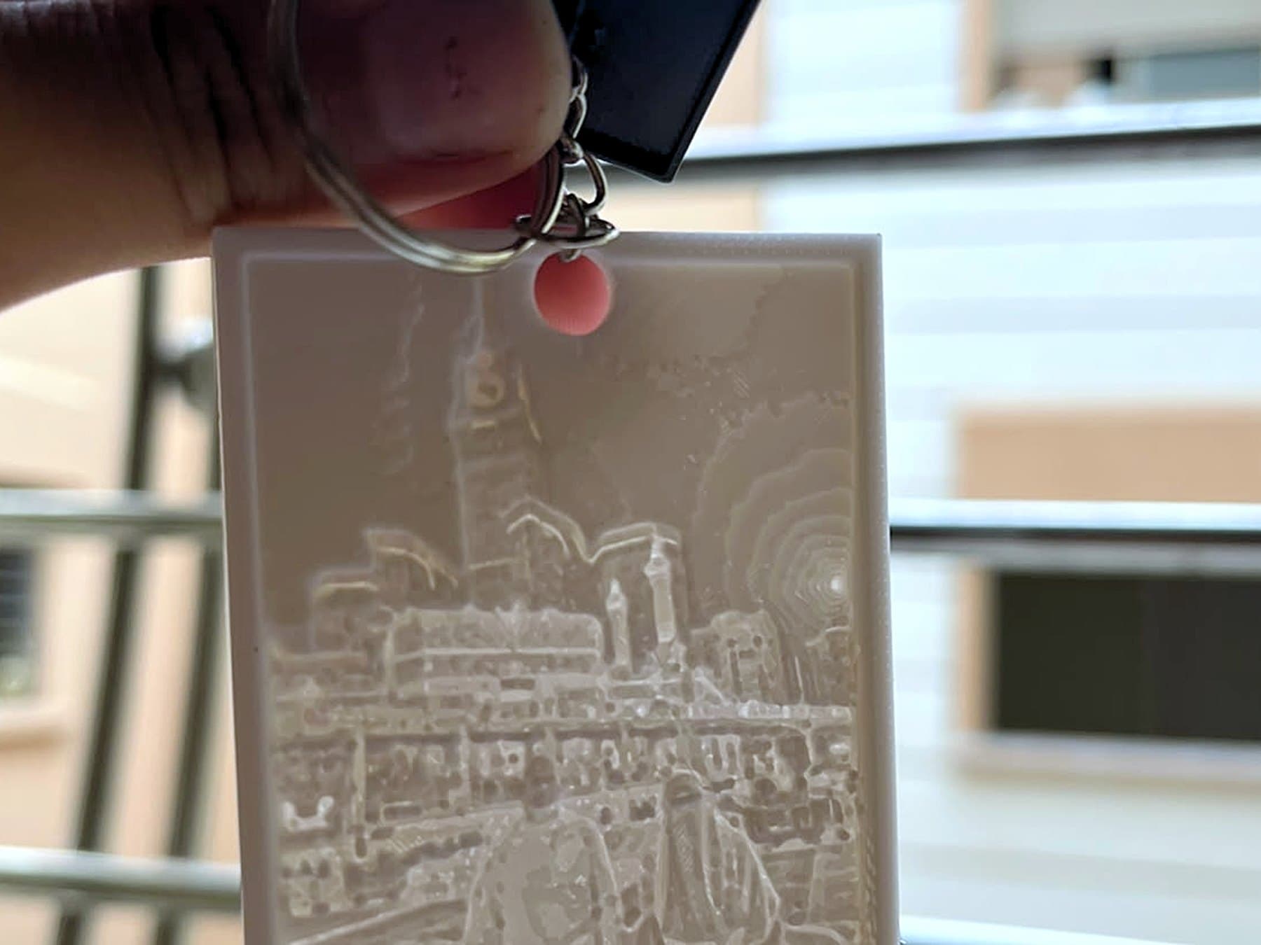 Porte-clés lithophane tenu devant la lumière, photo gravée apparaissant dans la matière