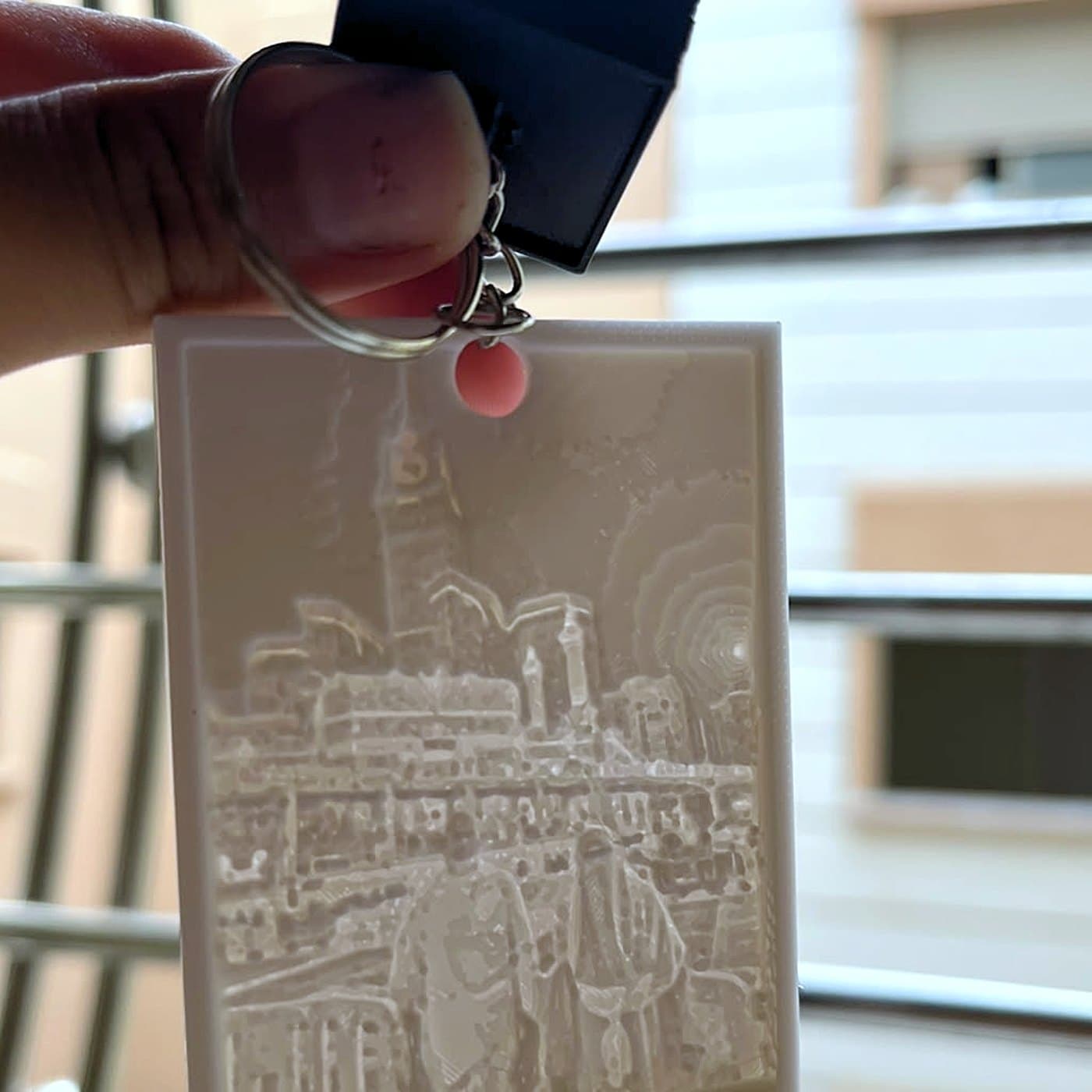 Porte-clés lithophane tenu à contre-jour, photo gravée visible dans la matière